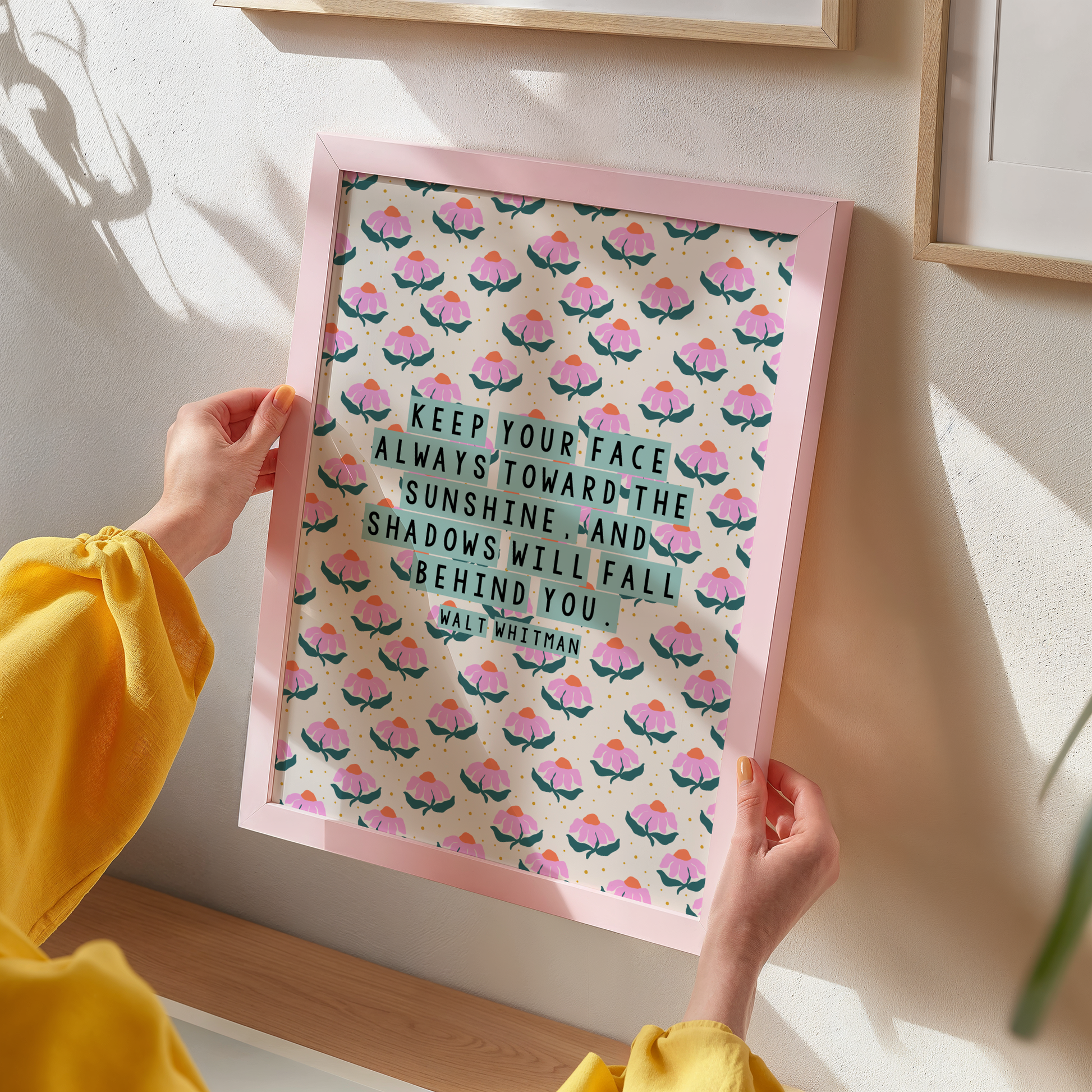 A pink, teal and cream floral patterned print, with a well known quote by Walt Whitman, saying keep our face always toward the sunshine, and the shadows will fall behind you.