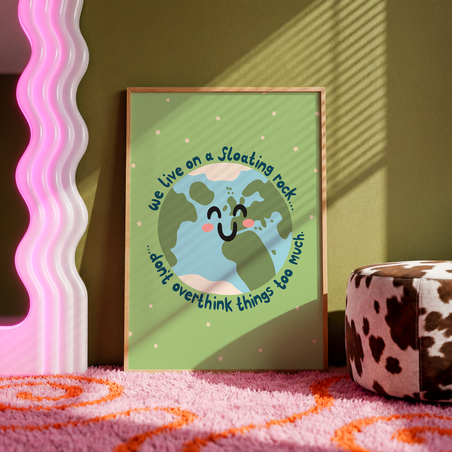 A green print with an illustration of a smiling planet earth. Around the earth is text that reads 'we live on a floating rock... don't overthink things too much.'