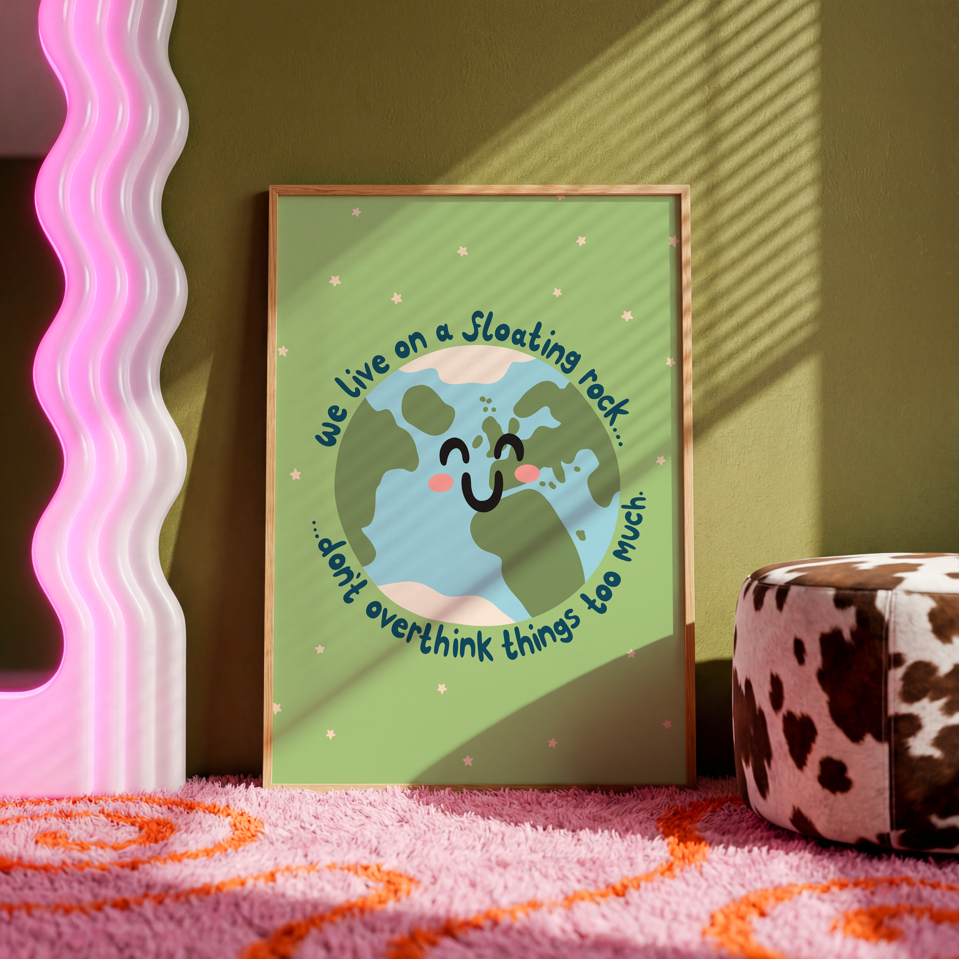A green print with an illustration of a smiling planet earth. Around the earth is text that reads 'we live on a floating rock... don't overthink things too much.'