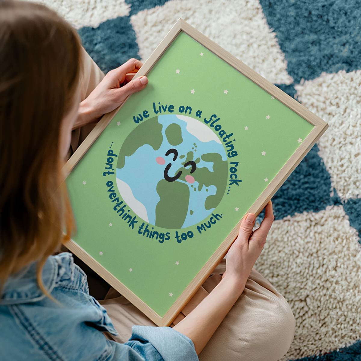 A green print with an illustration of a smiling planet earth. Around the earth is text that reads 'we live on a floating rock... don't overthink things too much.'