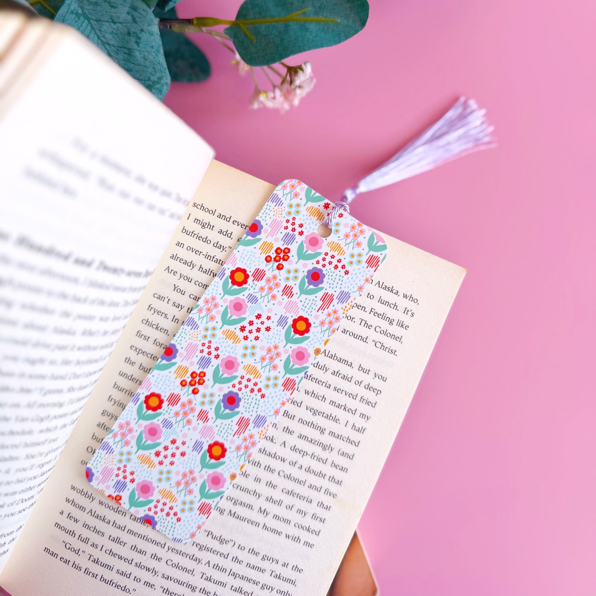 A brightly patterned floral bookmark with a coordinating purple tassel.