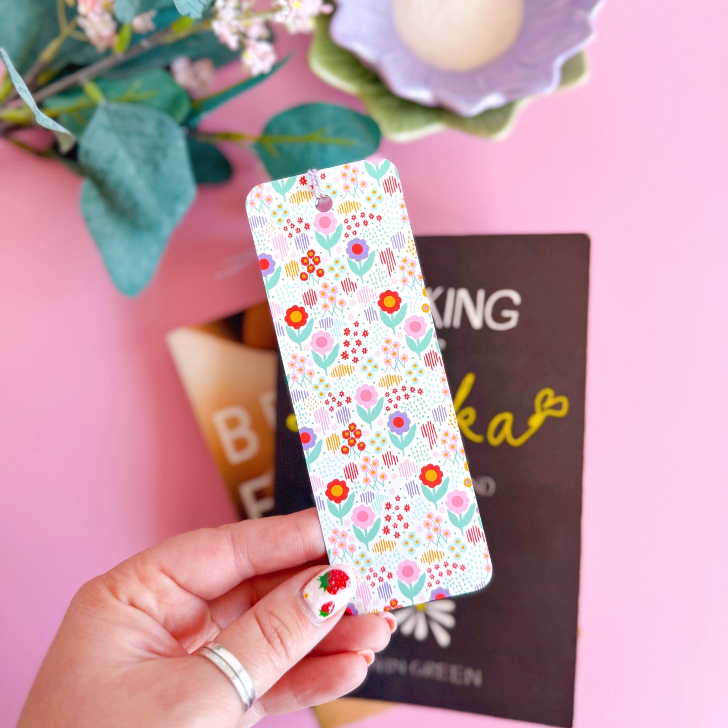 A brightly patterned floral bookmark with a coordinating purple tassel.