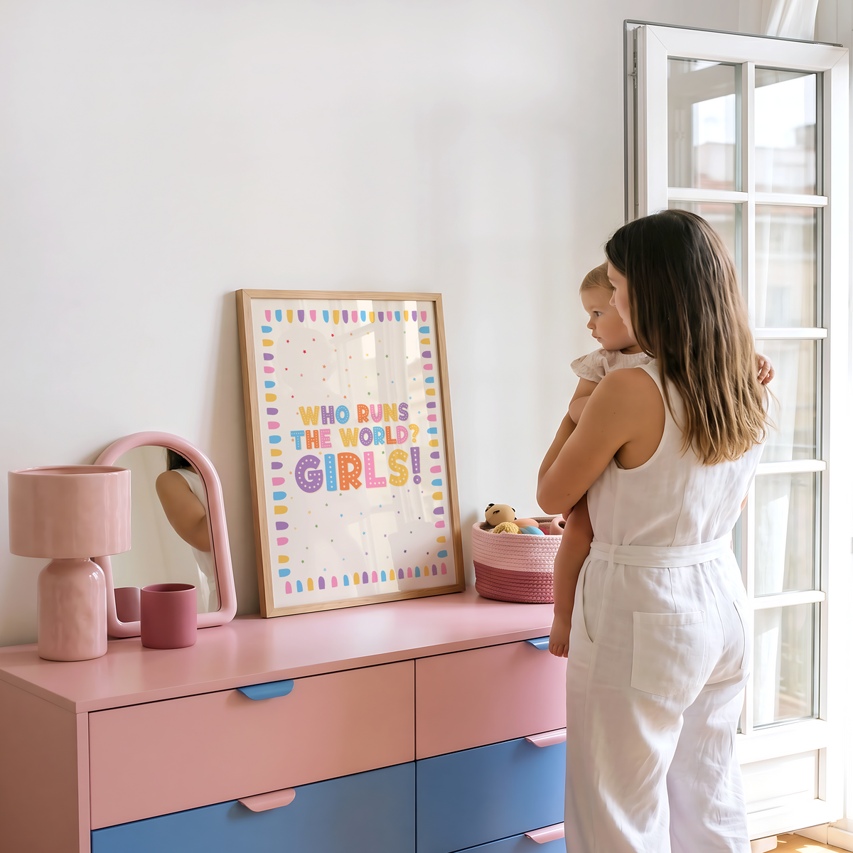 A nursery print with a colourful quote that reads 'who runs the world? GIRLS!' with a bright pastel coloured brush stroke border.