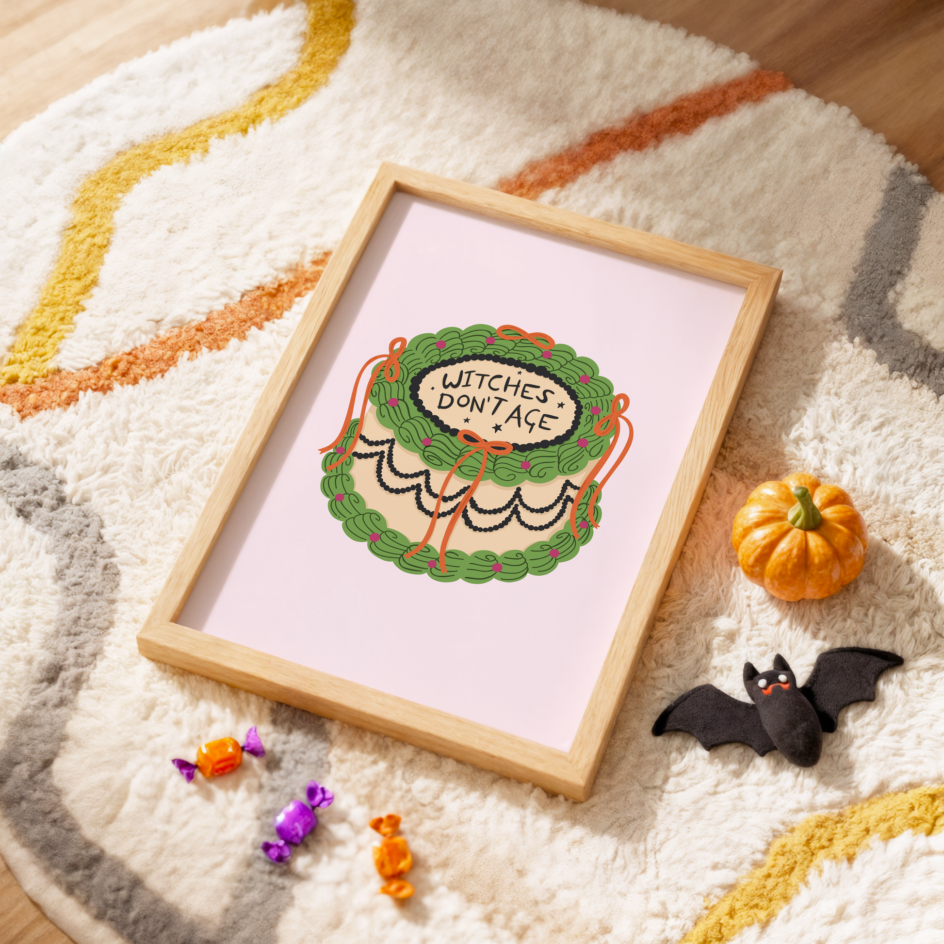 A Halloween print featuring an illustration of a cake, with green, orange and black icing. The words on top of the cake read 'witches don't age'.