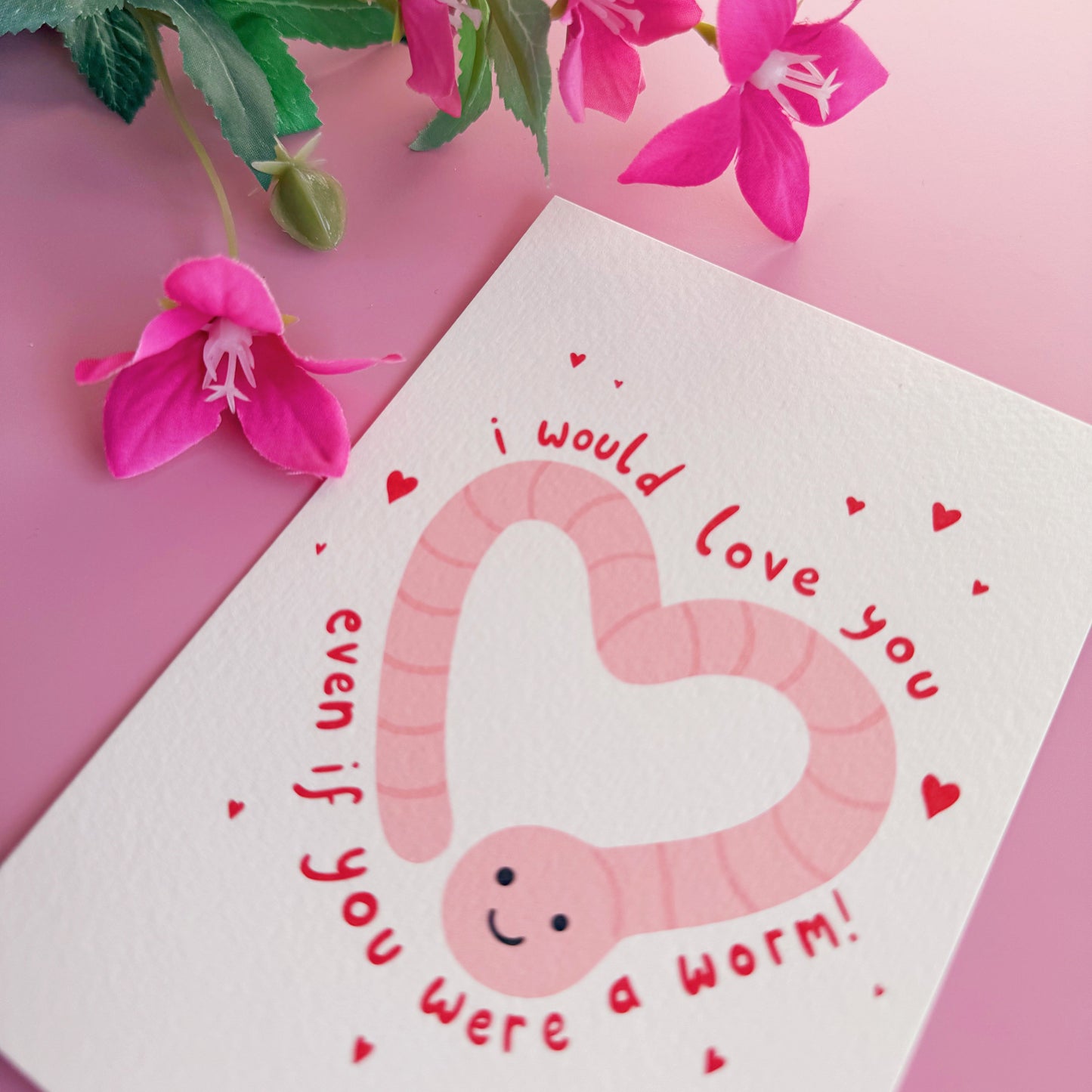 A textured postcard with an illustration of a worm in the shape of a heart, with the words 'I would love you even if you were a worm!' around the illustration.