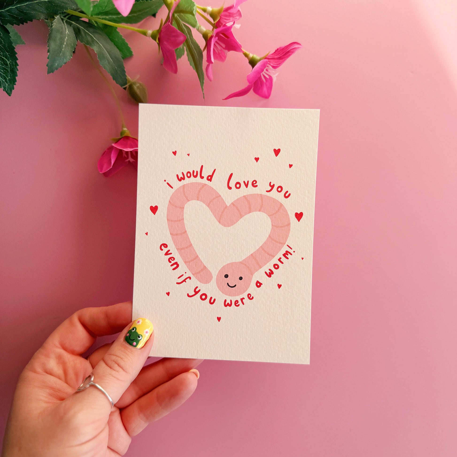 A textured postcard with an illustration of a worm in the shape of a heart, with the words 'I would love you even if you were a worm!' around the illustration.