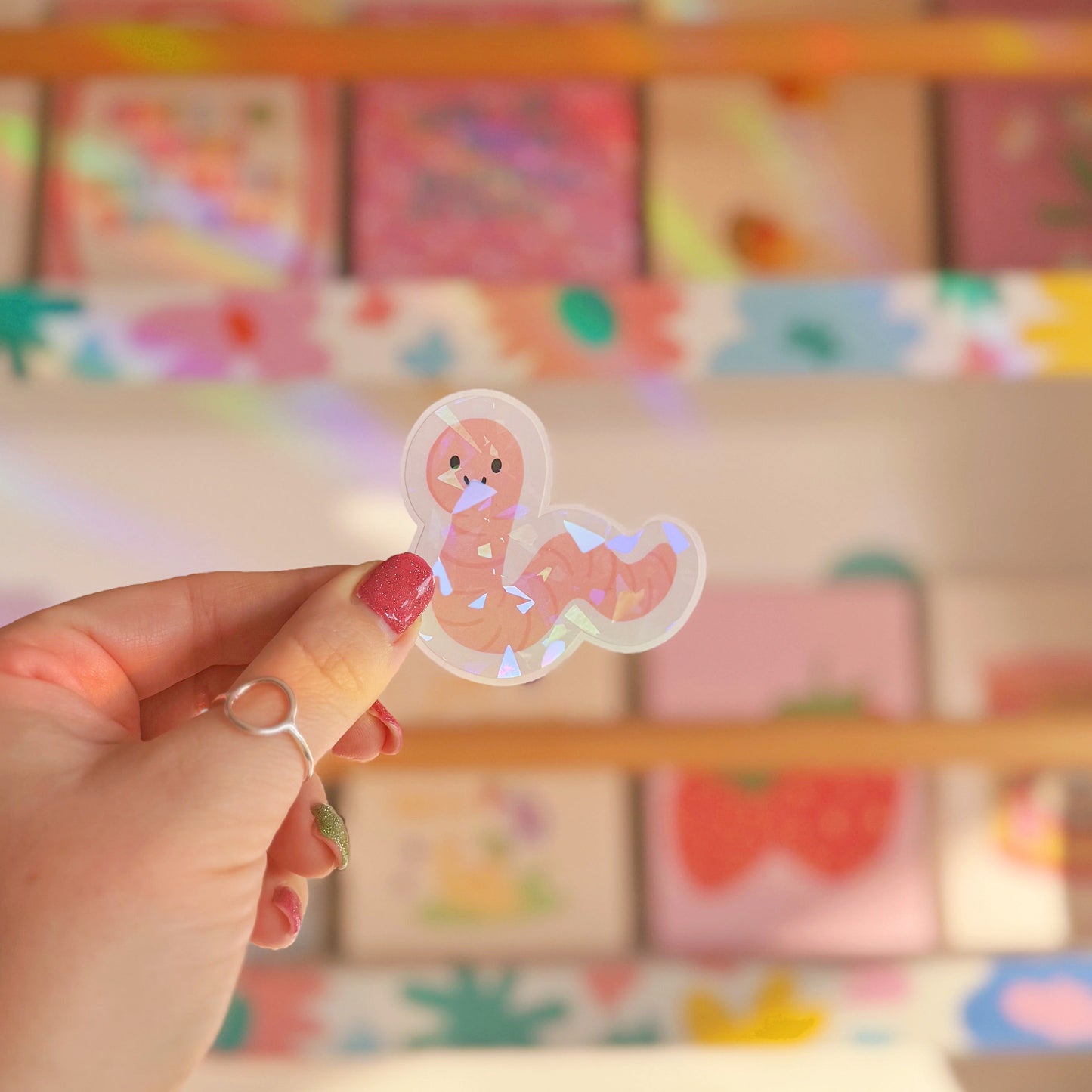 A holographic sticker featuring an illustration of a smiling worm.