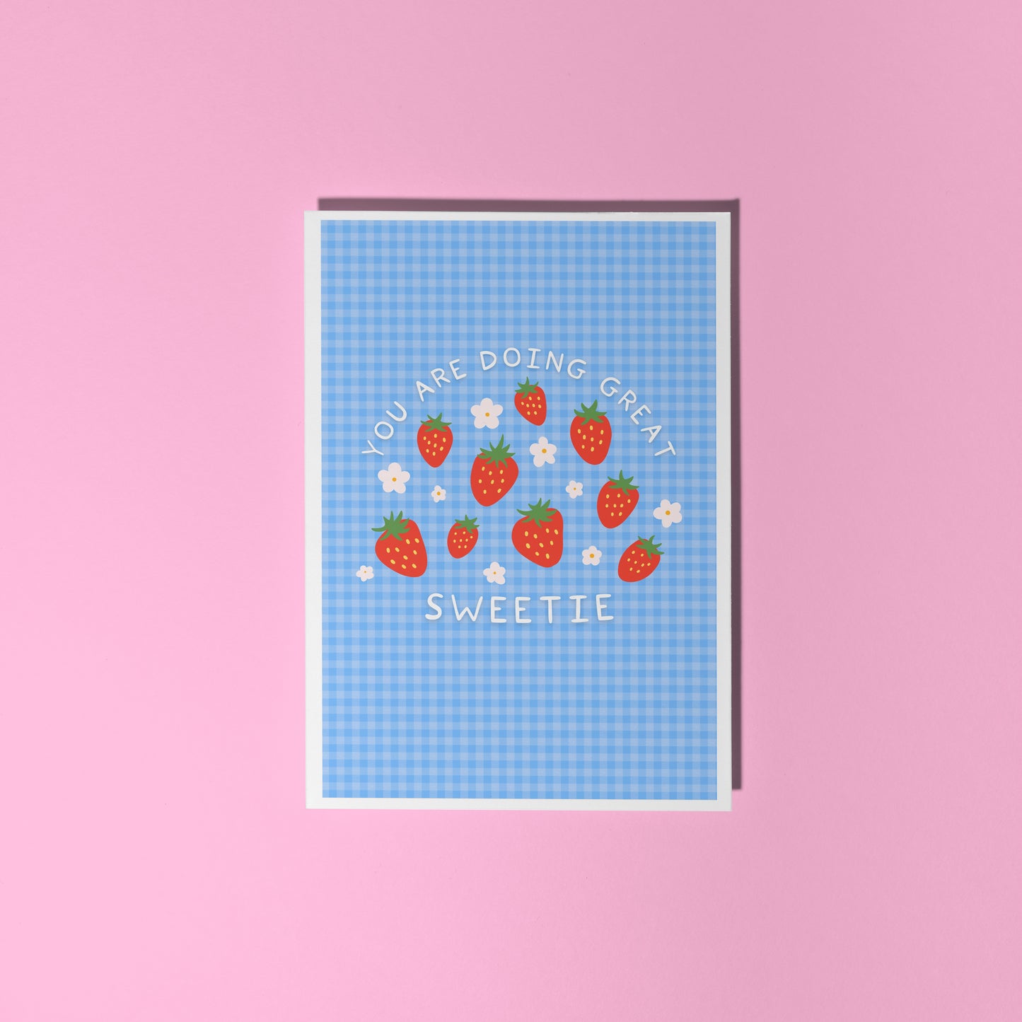 Card with strawberry design and text that reads 'you are doing great sweetie' on a blue gingham background