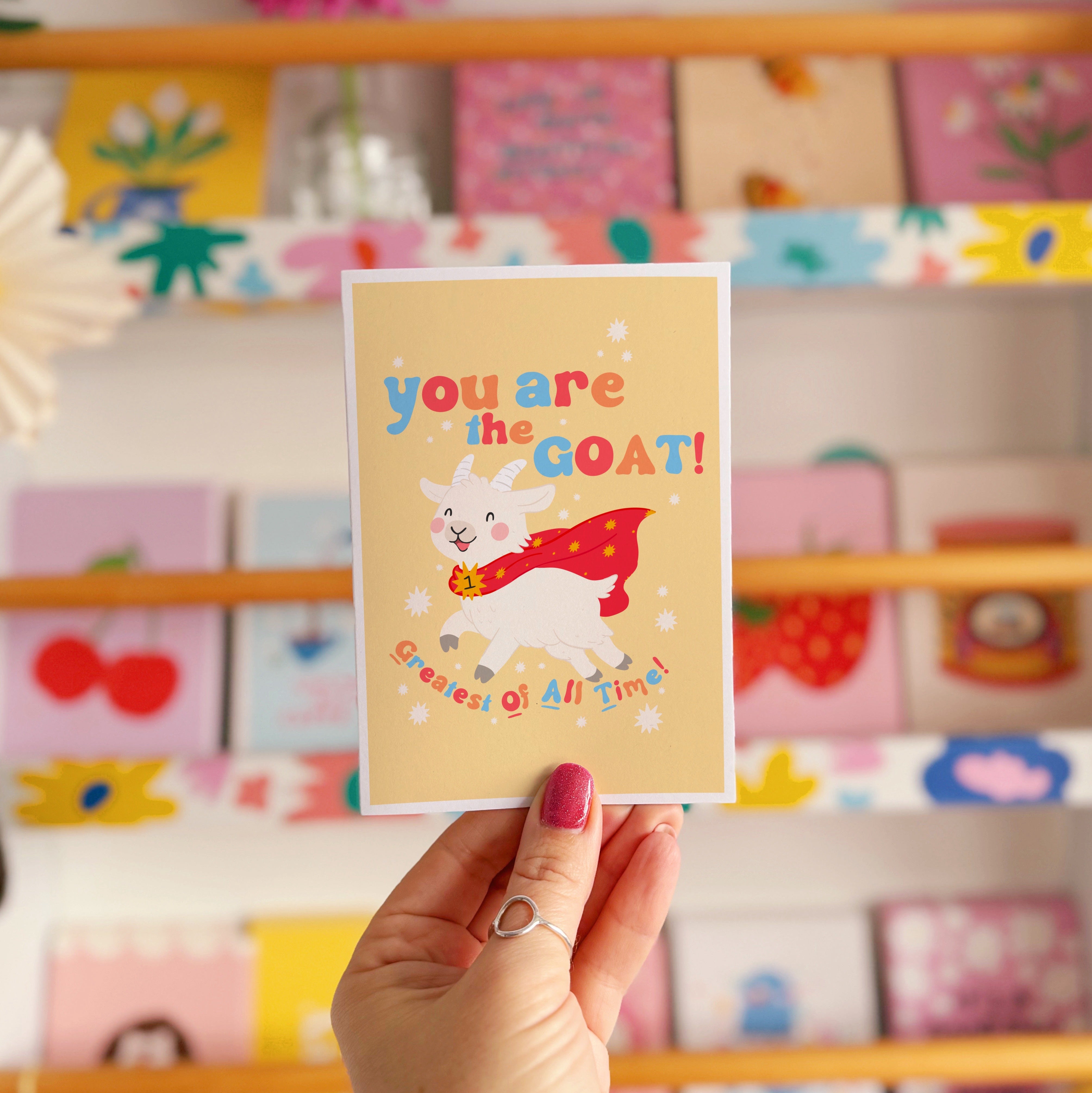 A greetings card with a goat illustration, and hand lettered text that reads 'you are the goat! (greatest of all time!)'.