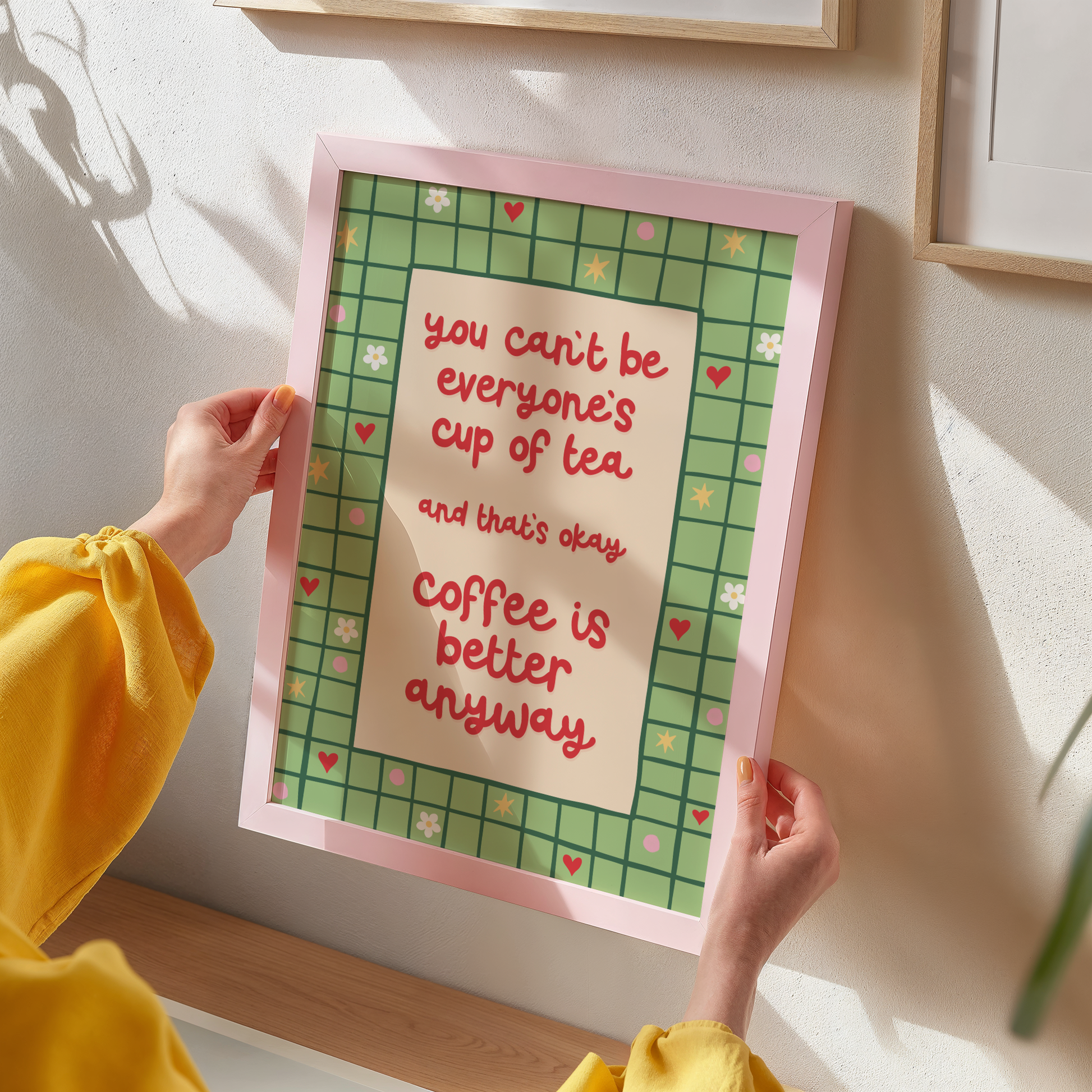 A green bordered print, with little doodles within the border, and a quote in red that reads 'you can't be everyone's cup of tea and that's okay. coffee is better anyway'.