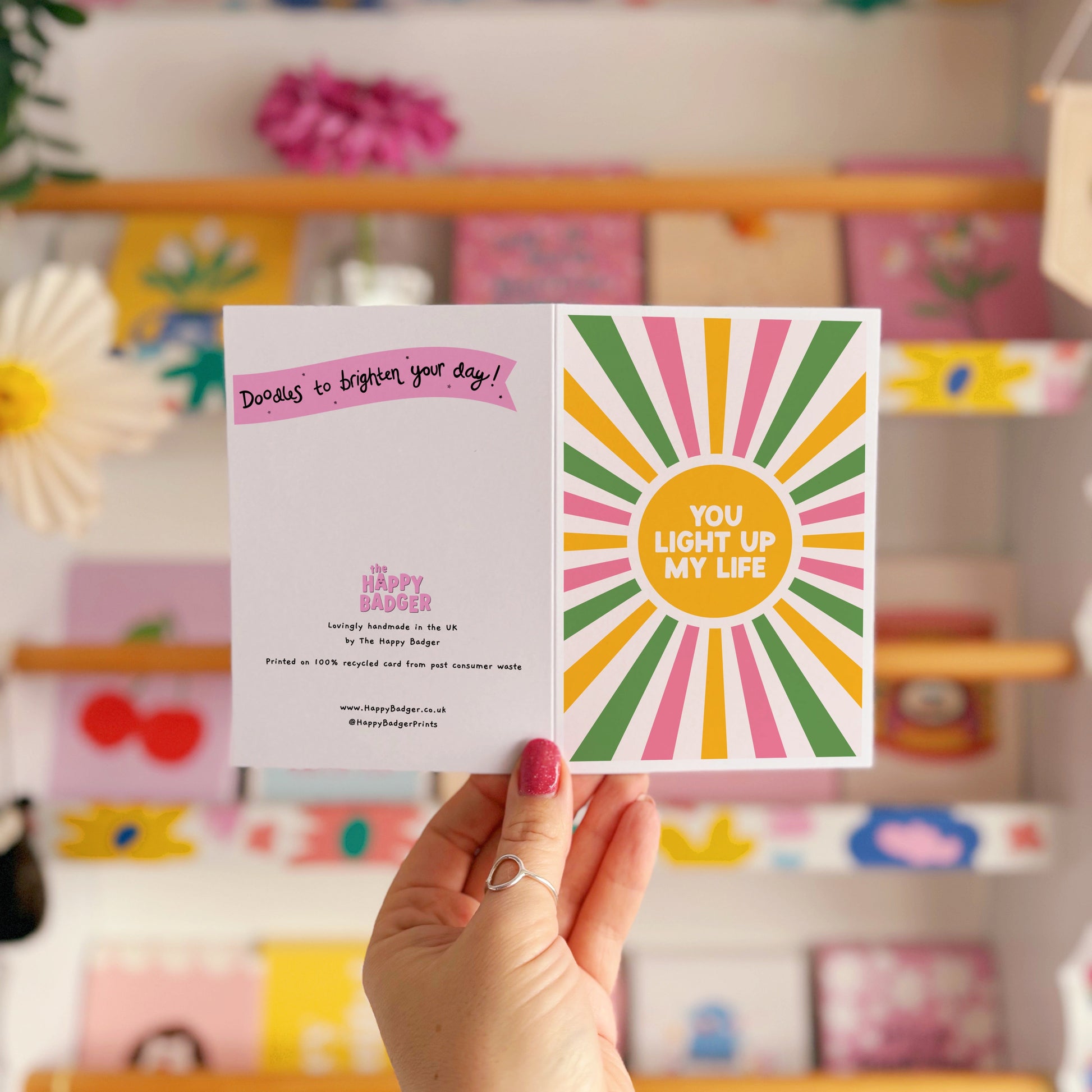 A pink, green and yellow star burst design with the words 'you light up my life' in the centre.