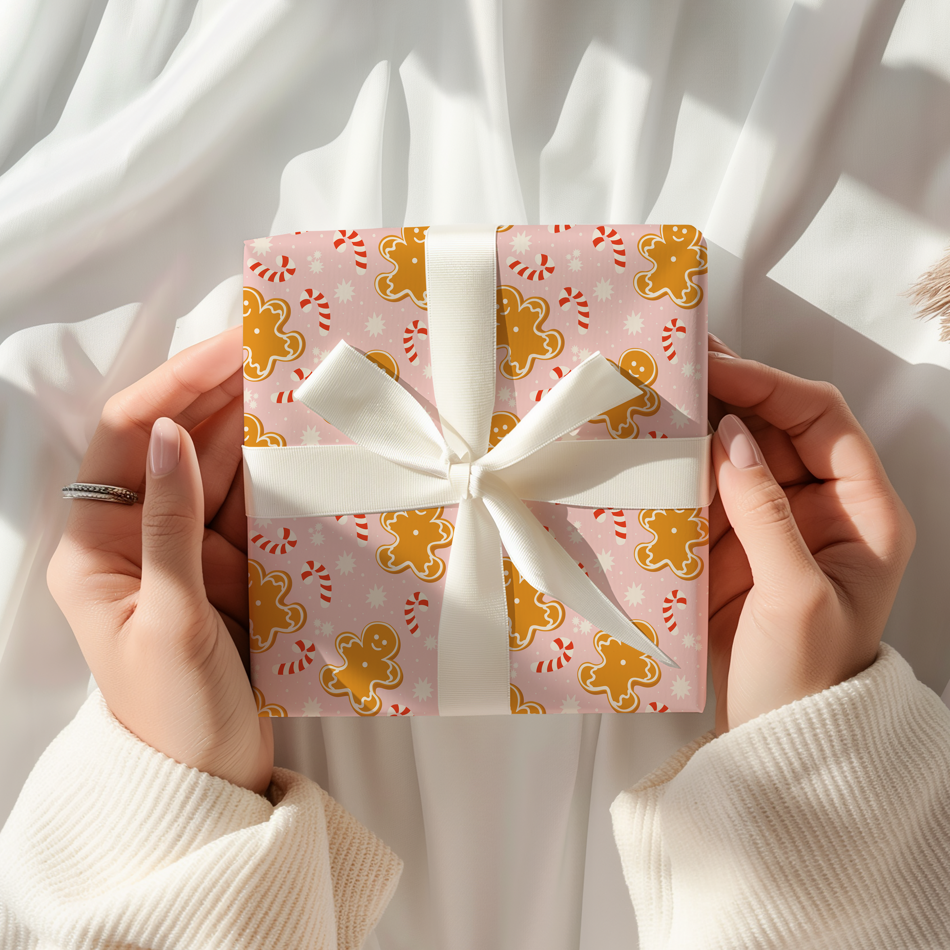 Gift box with a white ribbon held by hands against a white background