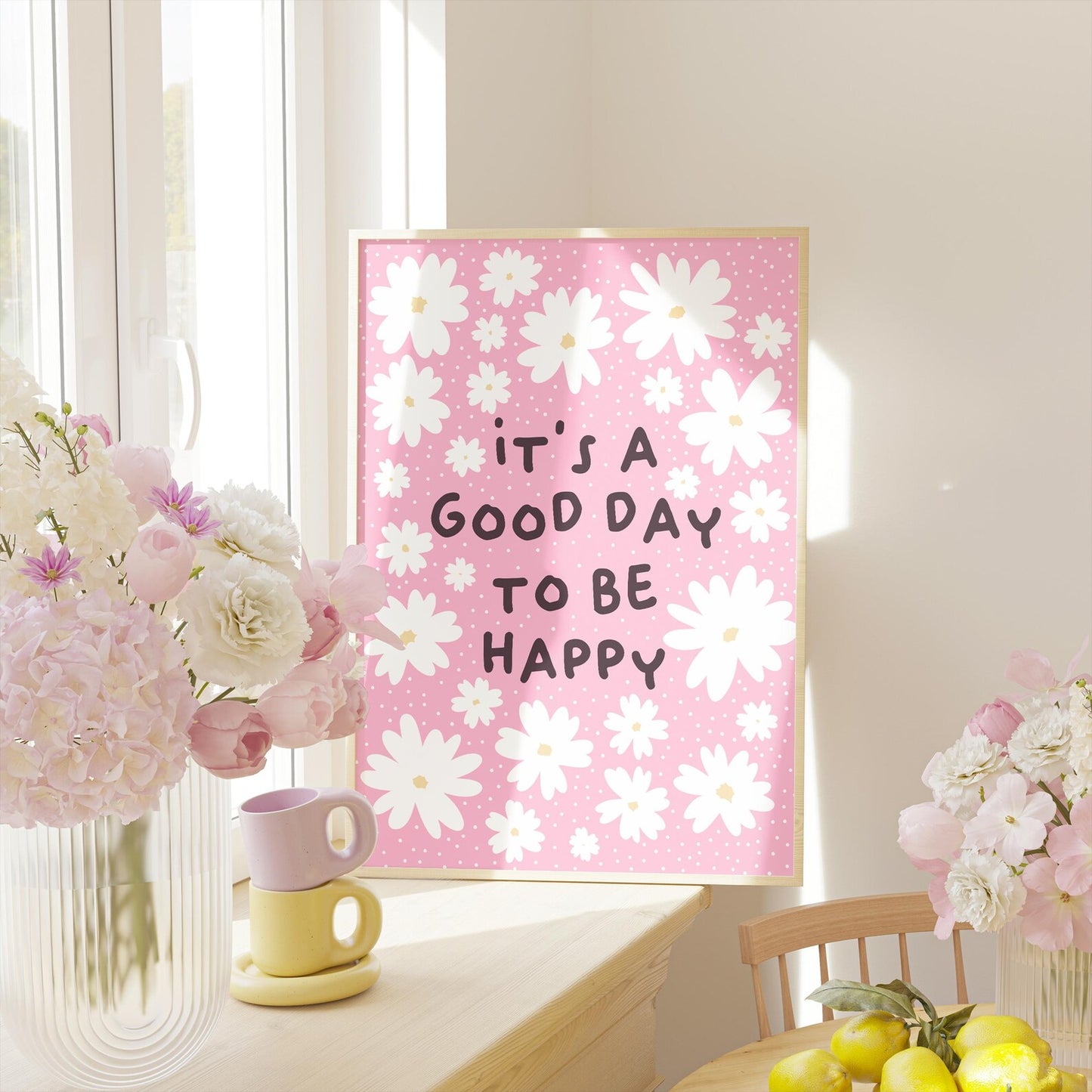 A pink print with several white daisies, surrounding a positivity message of 'it's a good day to be happy'.