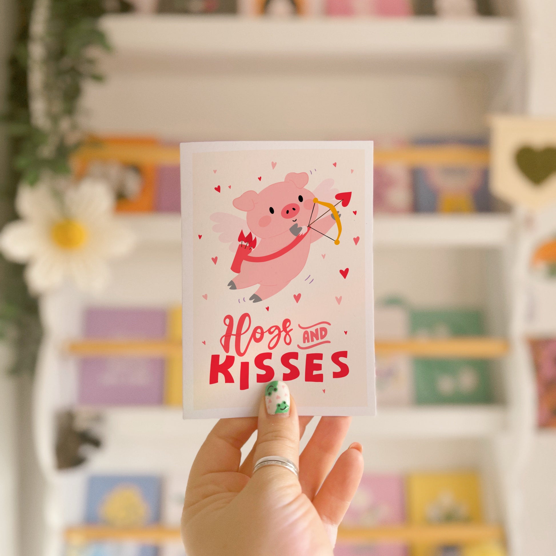 Card with a pig illustration dressed as cupid, with 'Hog and Kisses' hand written on the front of the card.