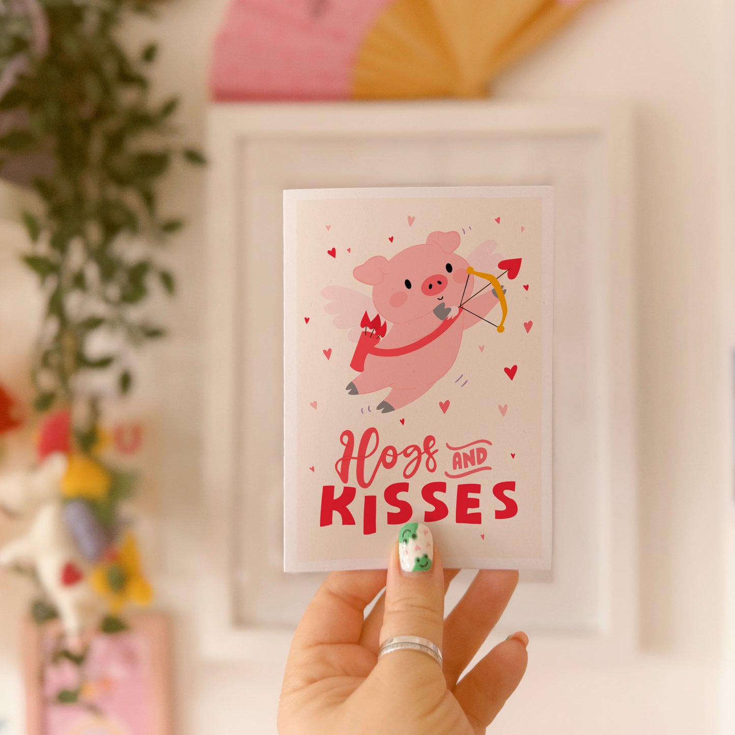 Card with a pig illustration dressed as cupid, with 'Hog and Kisses' hand written on the front of the card.