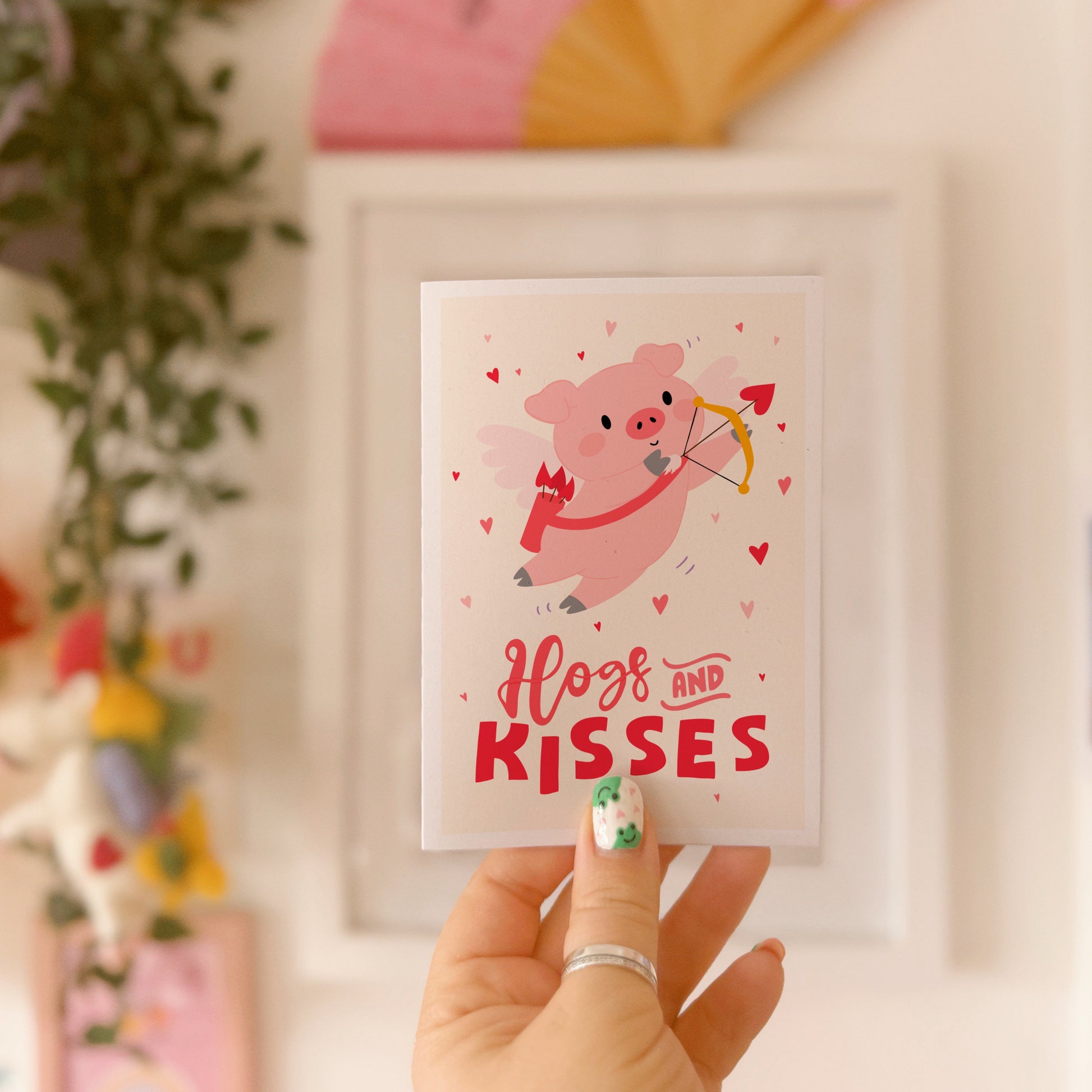 Card with a pig illustration dressed as cupid, with 'Hog and Kisses' hand written on the front of the card.