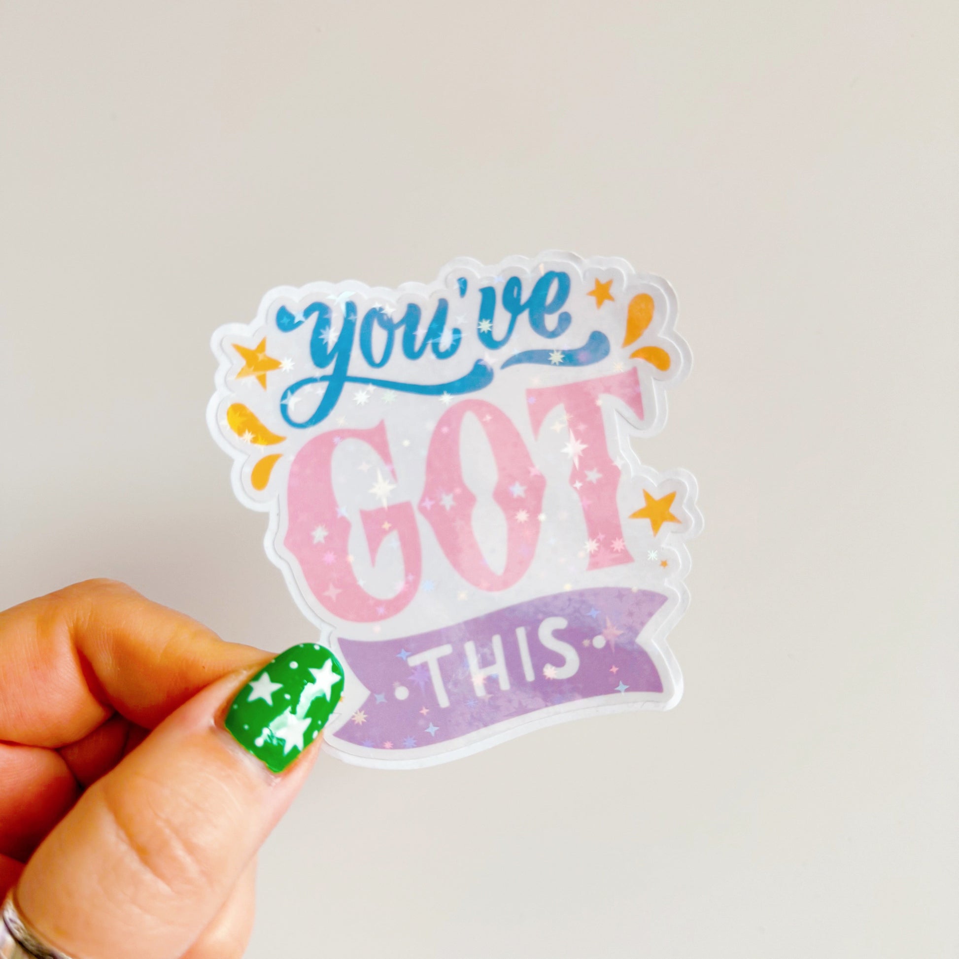 A holographic sticker, that says 'You've Got This' in pink blue and purple colours.