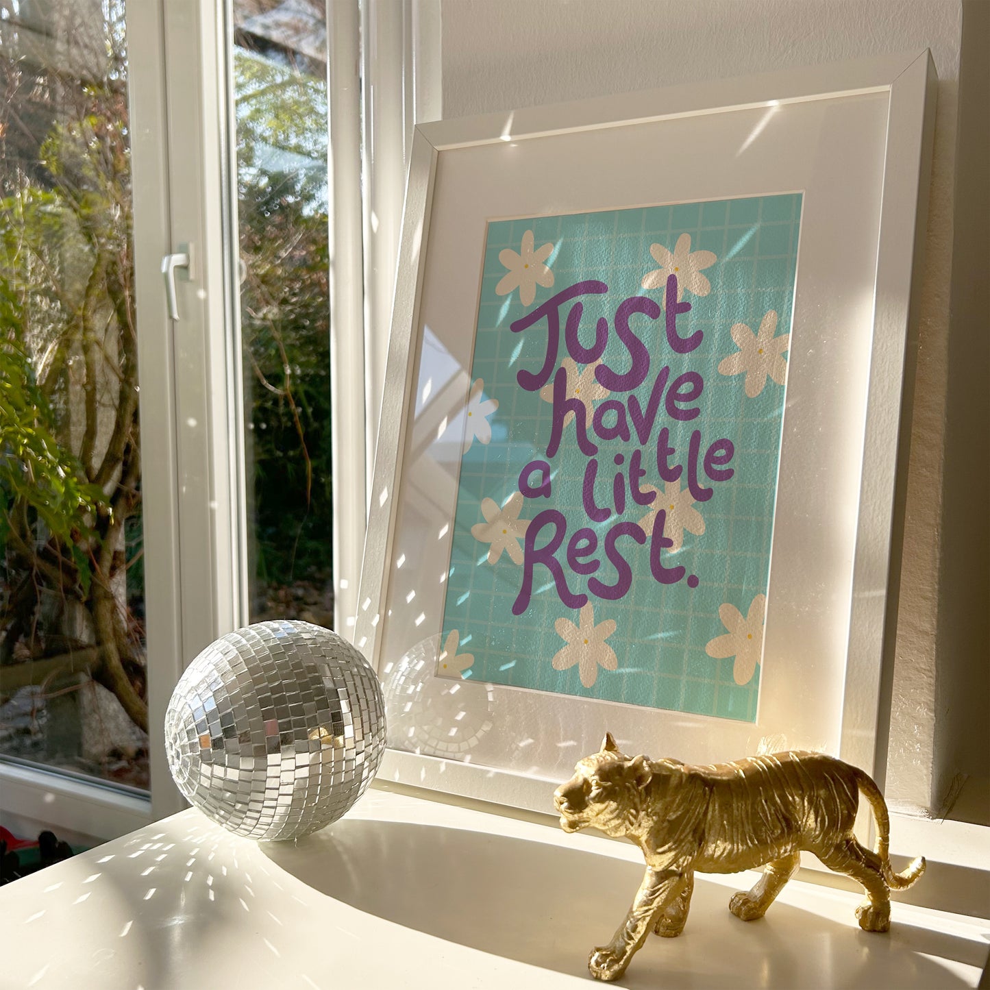 A blue print with a positive quote about resting, decorated with white hand drawn flowers.