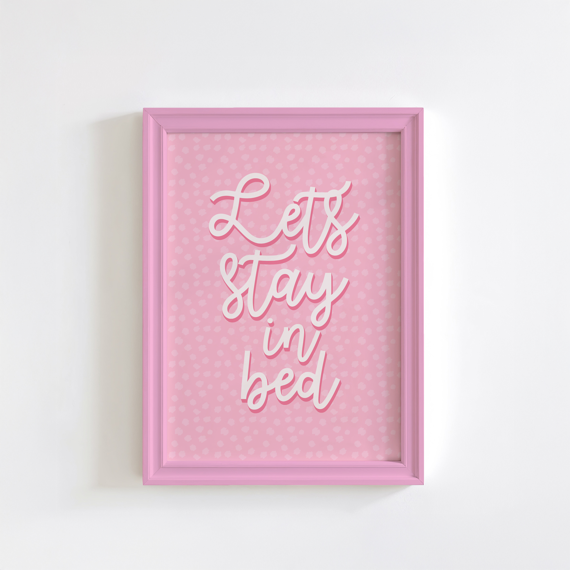A pink polka dot print, with the words 'lets stay in bed' in a script font in the centre.
