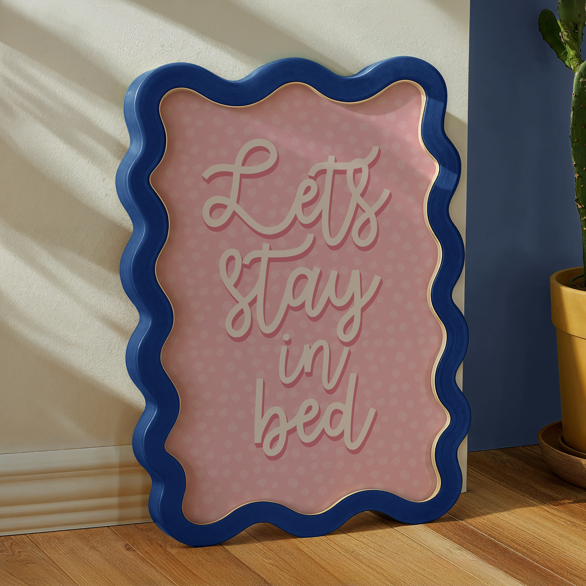 A pink polka dot print, with the words 'lets stay in bed' in a script font in the centre.