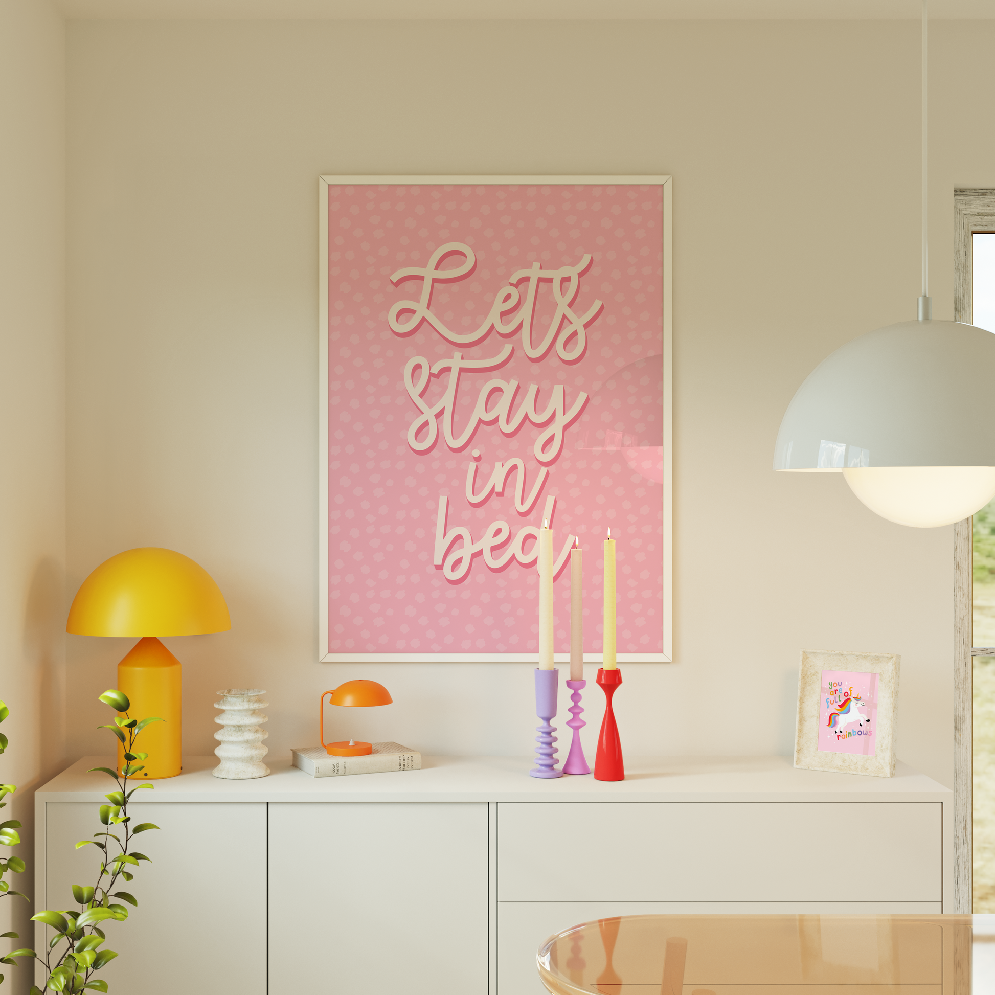 A pink polka dot print, with the words 'lets stay in bed' in a script font in the centre.