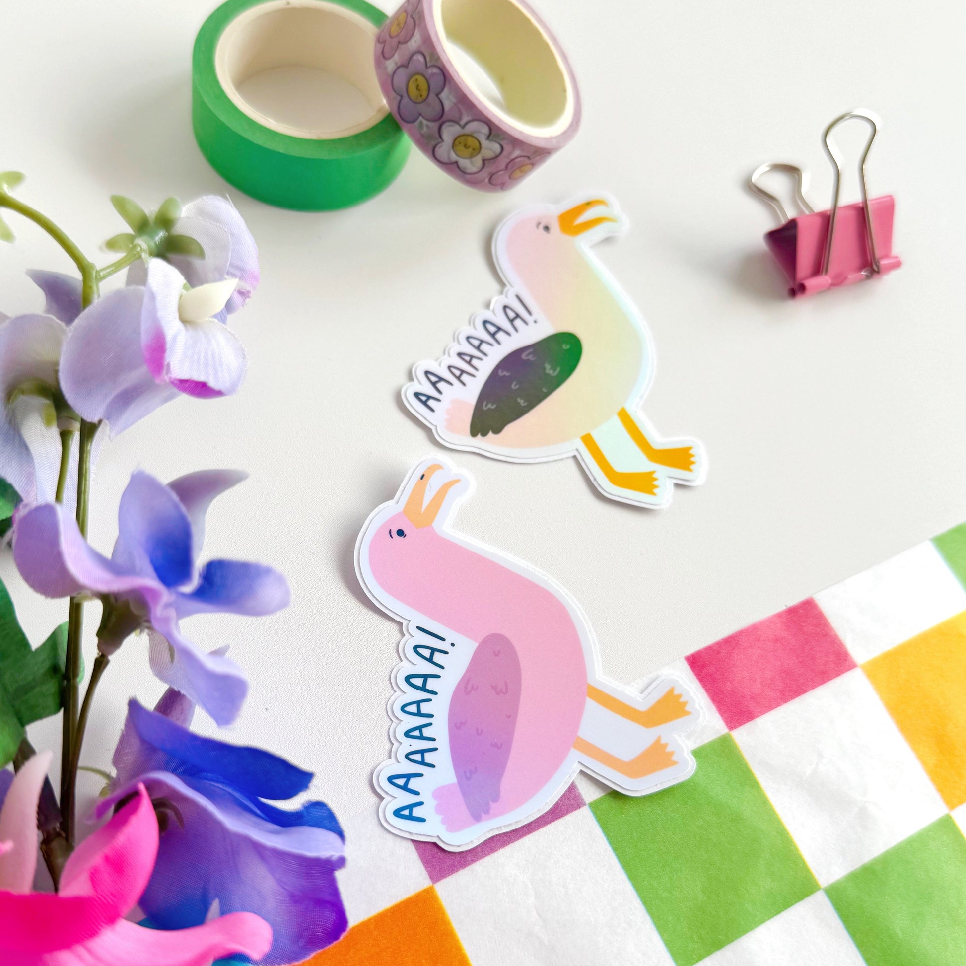 An image showing two holographic stickers of seagulls, one in pink one in more life-like colours. The text reads 'AAAAAAA!' as if the seagulls are screaming.