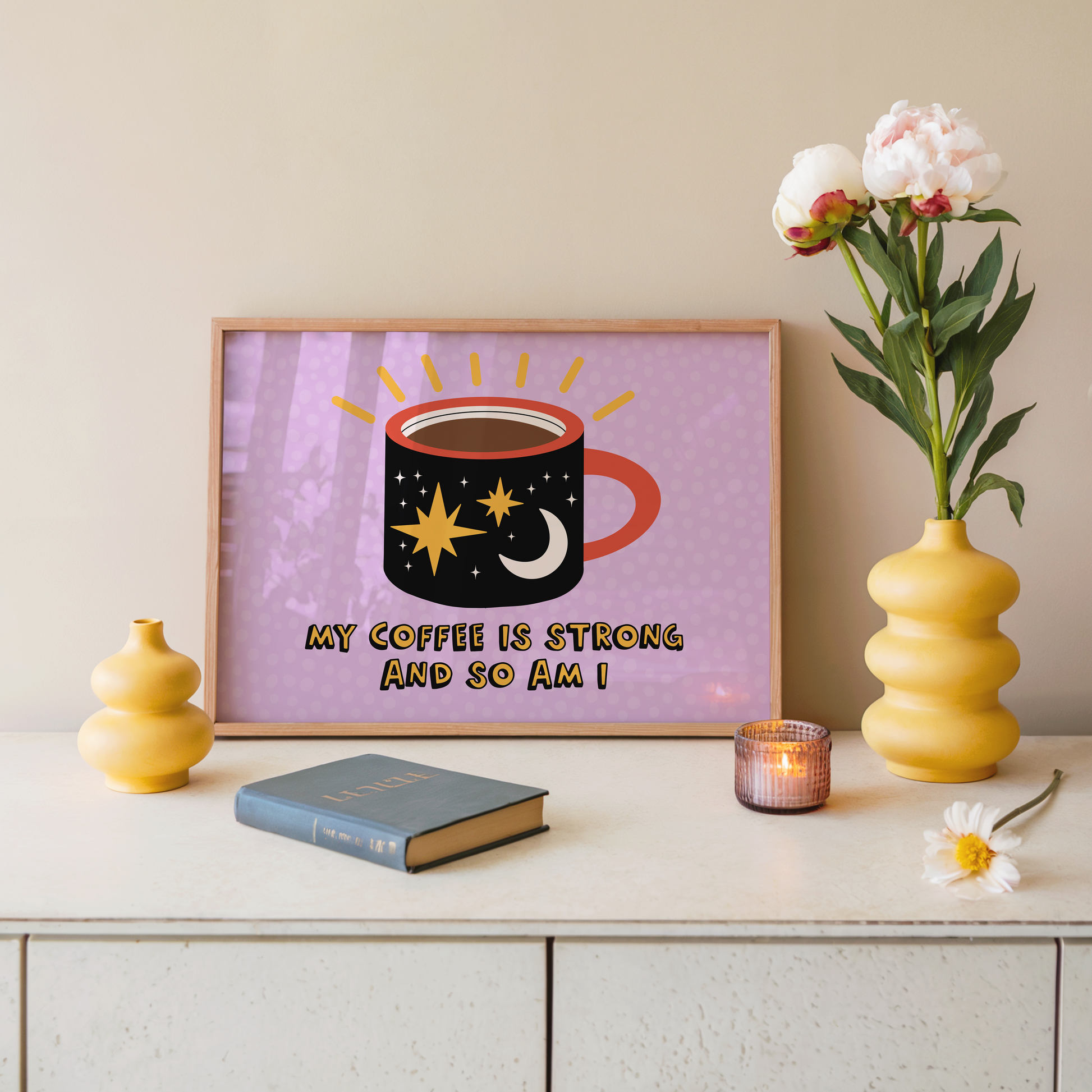 A framed print with a vibrant illustration of a coffee mug, with stars and a sun motif, and the text 'MY COFFEE IS STRONG AND SO AM I!' on a purple background.