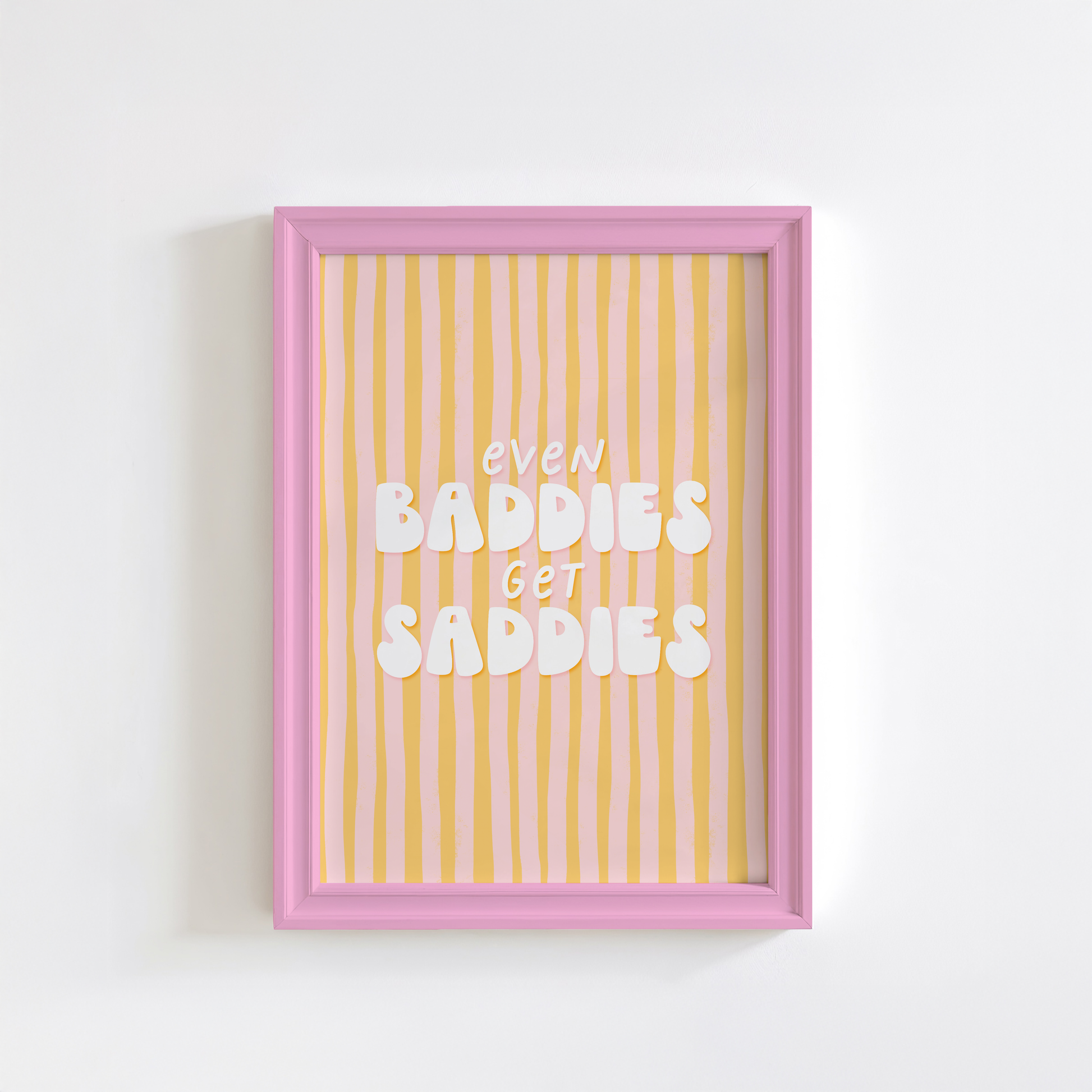 A funny quote print saying Even Baddies Get Baddies Print on a yellow and pink striped background.