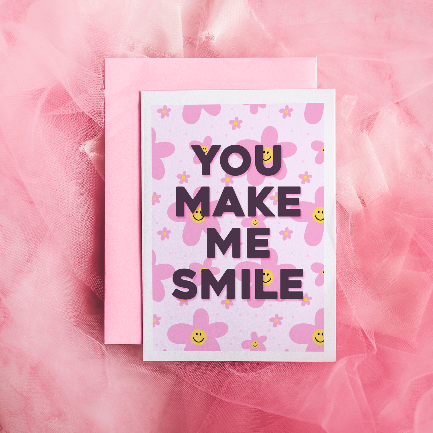 a card with pink smiling daisies on the background, and black text reading 'you make me smile'.