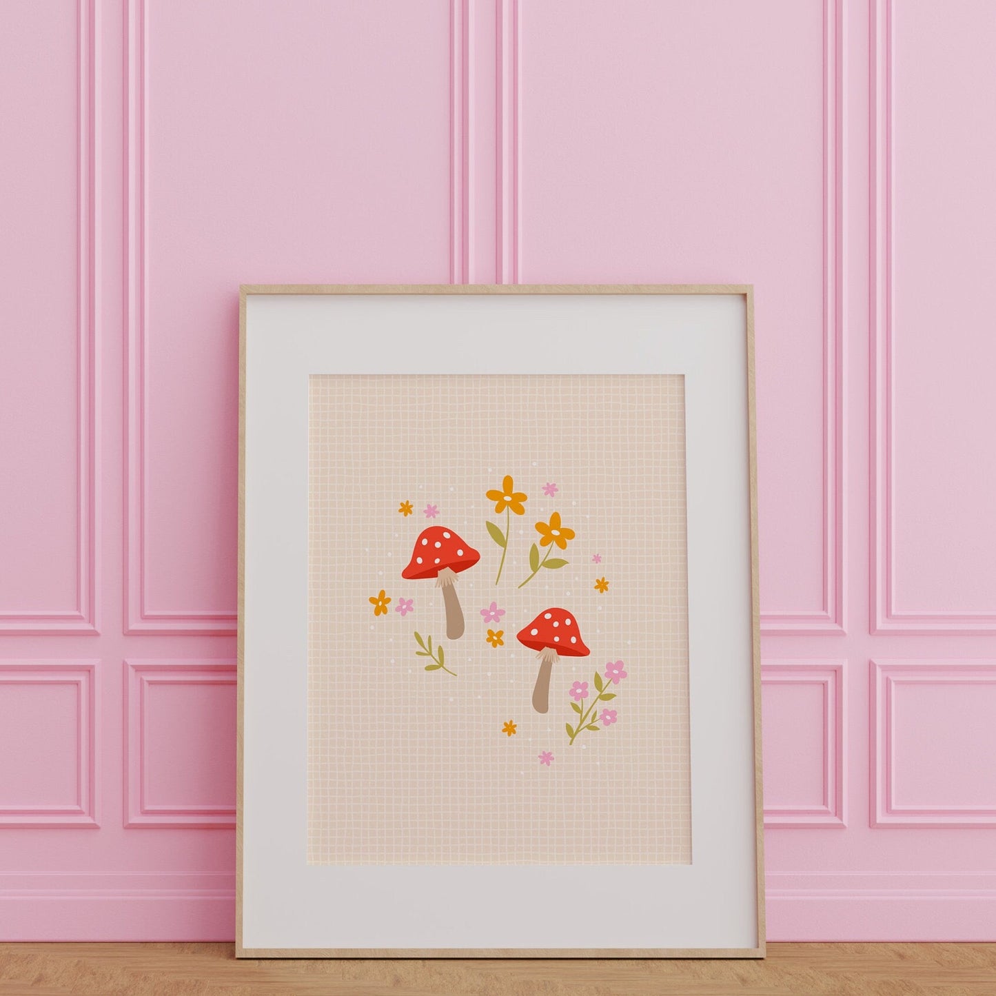 An illustration of a two cute mushrooms in shades of red and pink, surrounded by floral illustrations, shown in a frame.
