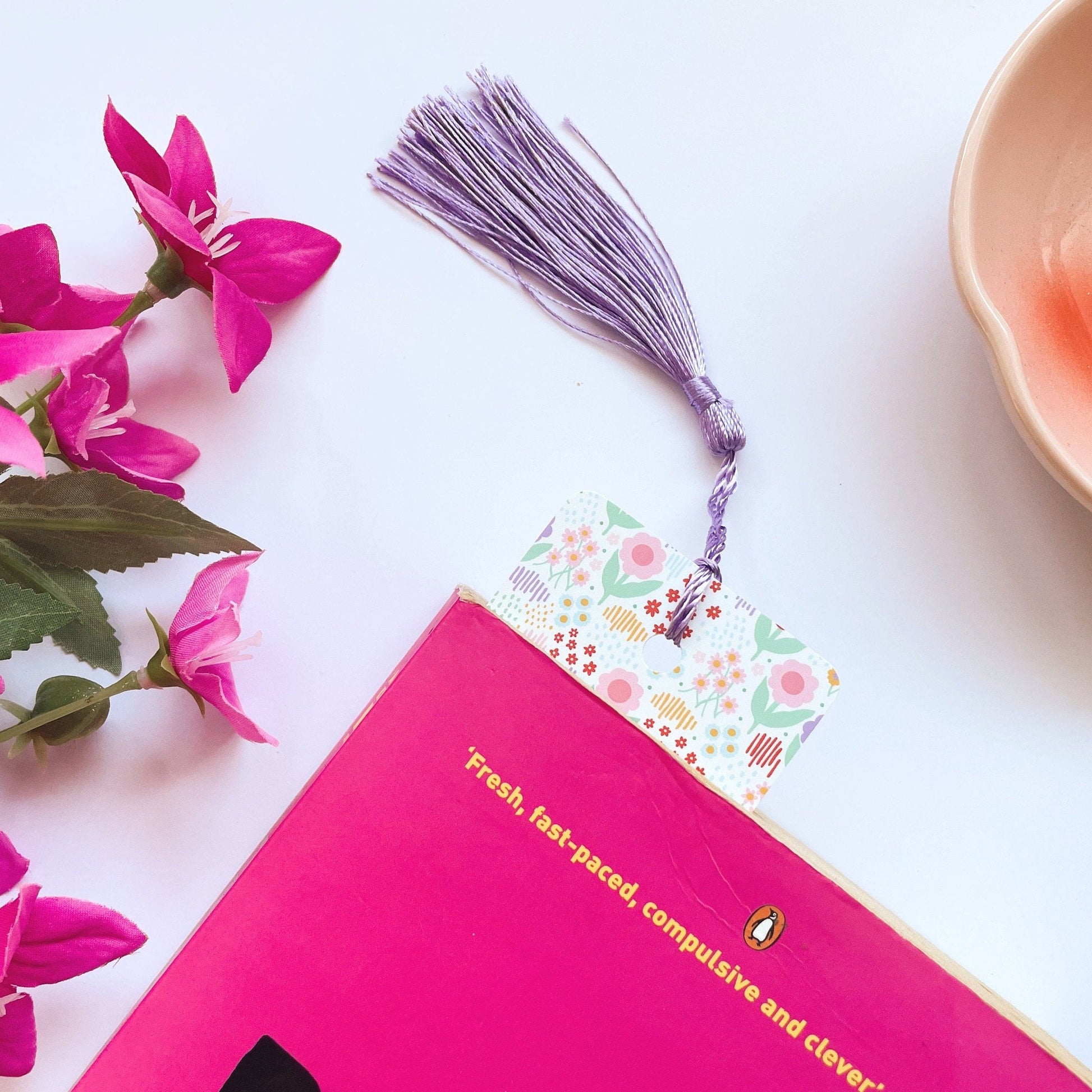 A picture of a brightly coloured floral patterned bookmark, with a coordinating purple tassel.