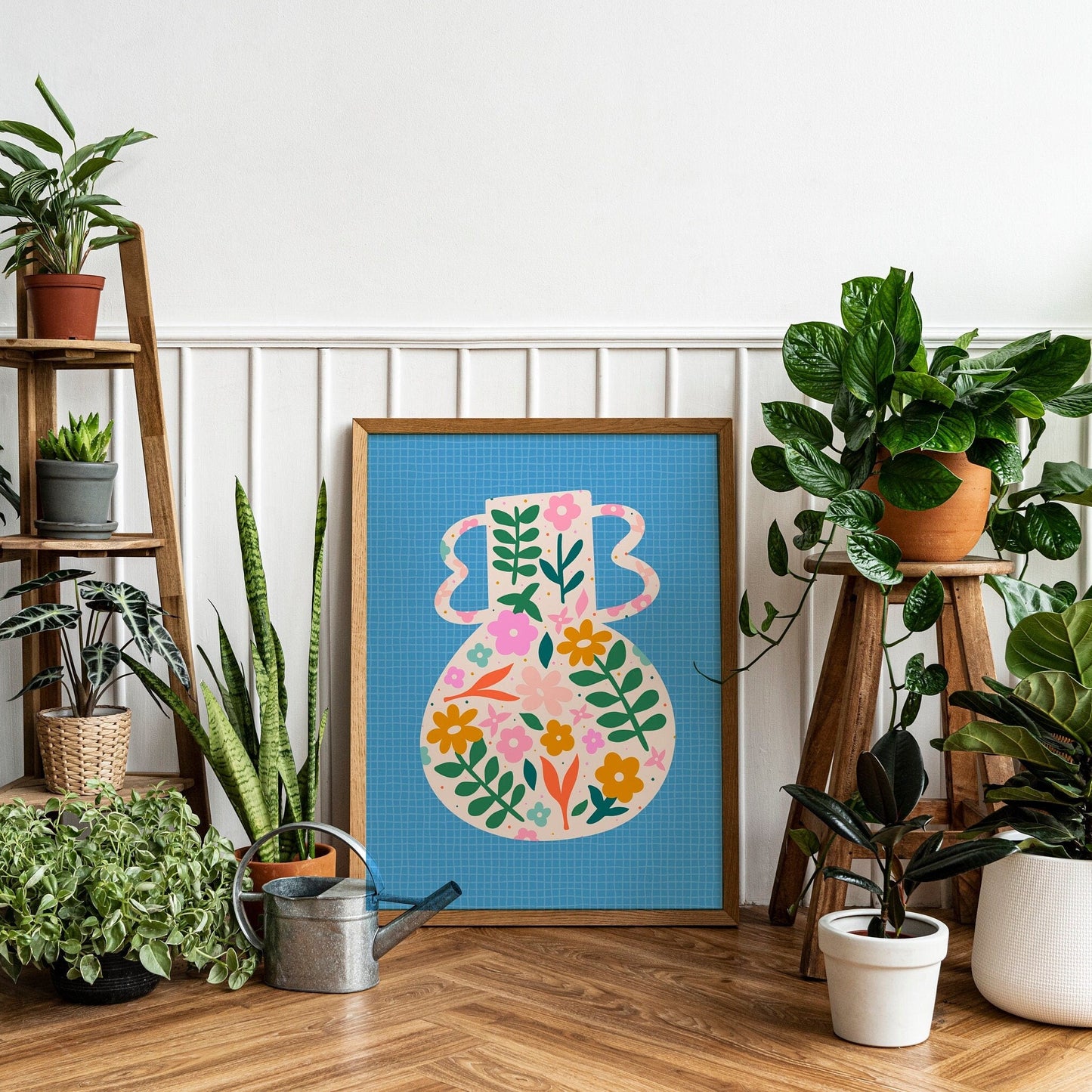 A blue art print featuring a vibrant vase illustration with floral patterns against a blue textured background, presented against a white wall.