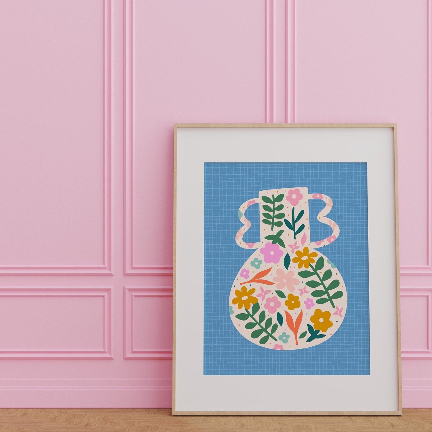 A blue art print featuring a vibrant vase illustration with floral patterns against a blue textured background, presented against a white wall.