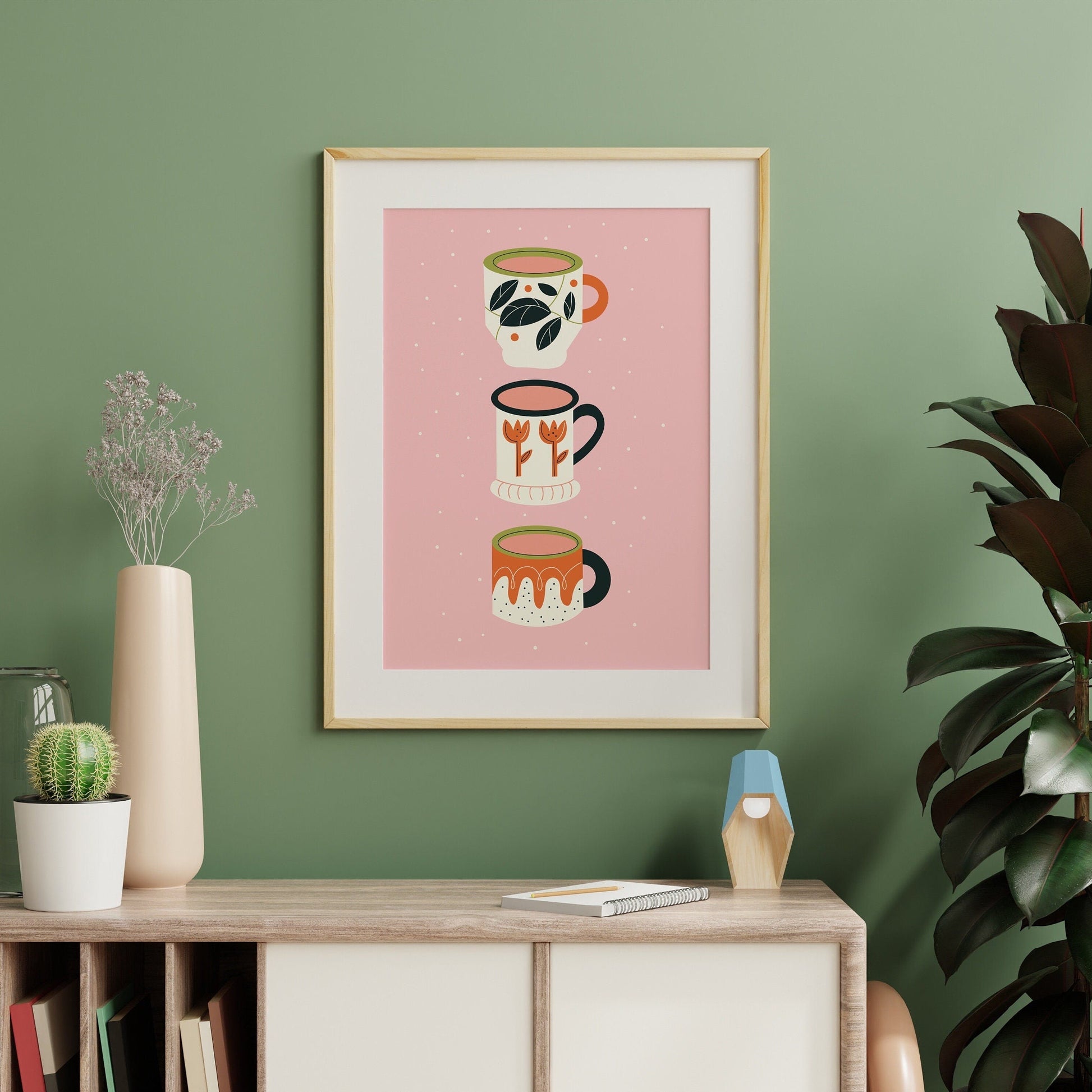 An illustration print of three quirky mug designs, in orange, ream, black and green on a pink background.