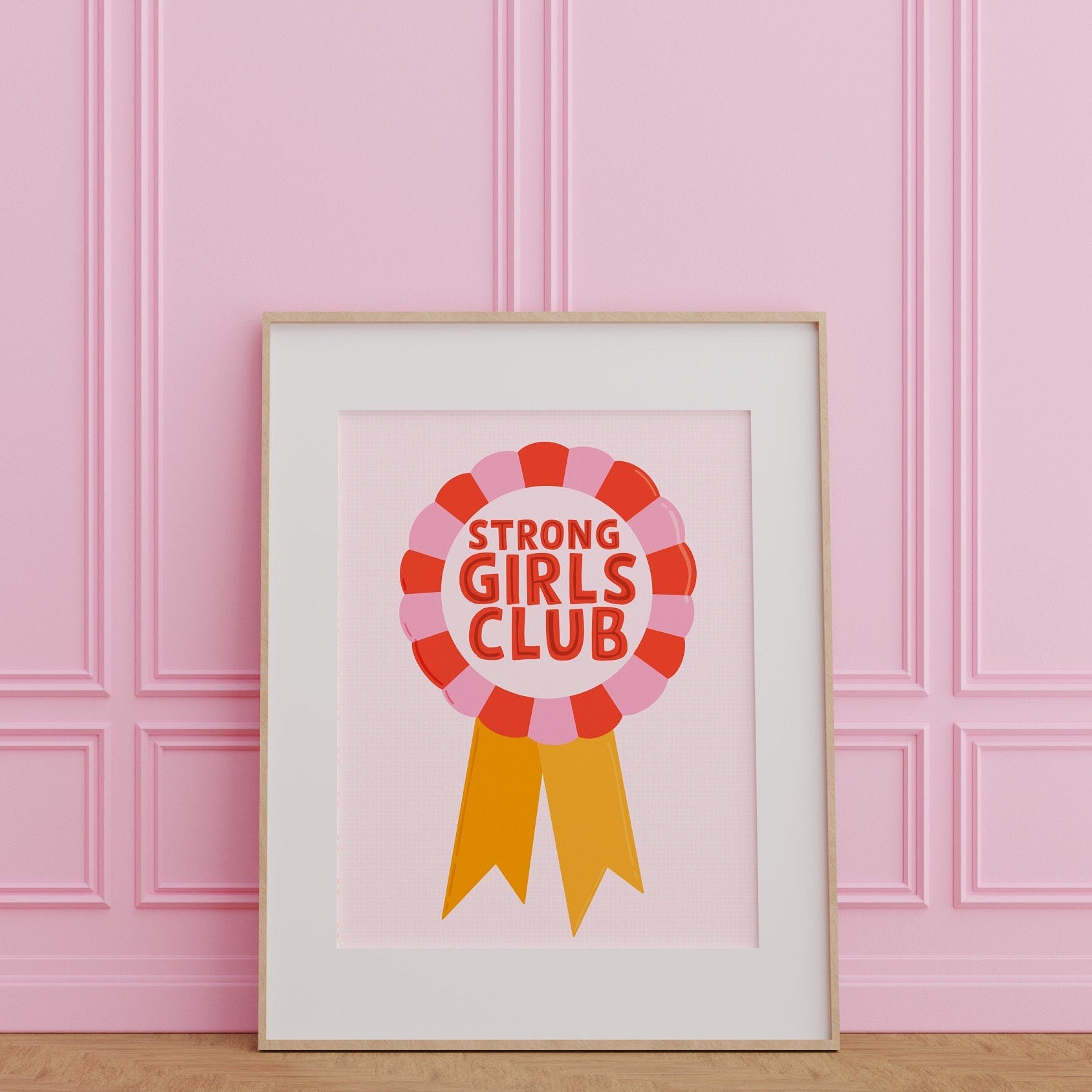 An illustration of a rosette style award, in red, pink and yellow. The award has the words 'Strong Girls Club' written in the centre of the rosette.